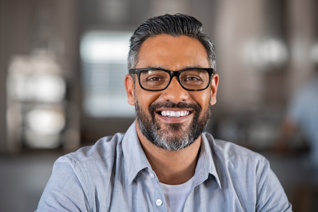 Smiling mature Indian man wearing spectacles and looking at camera.