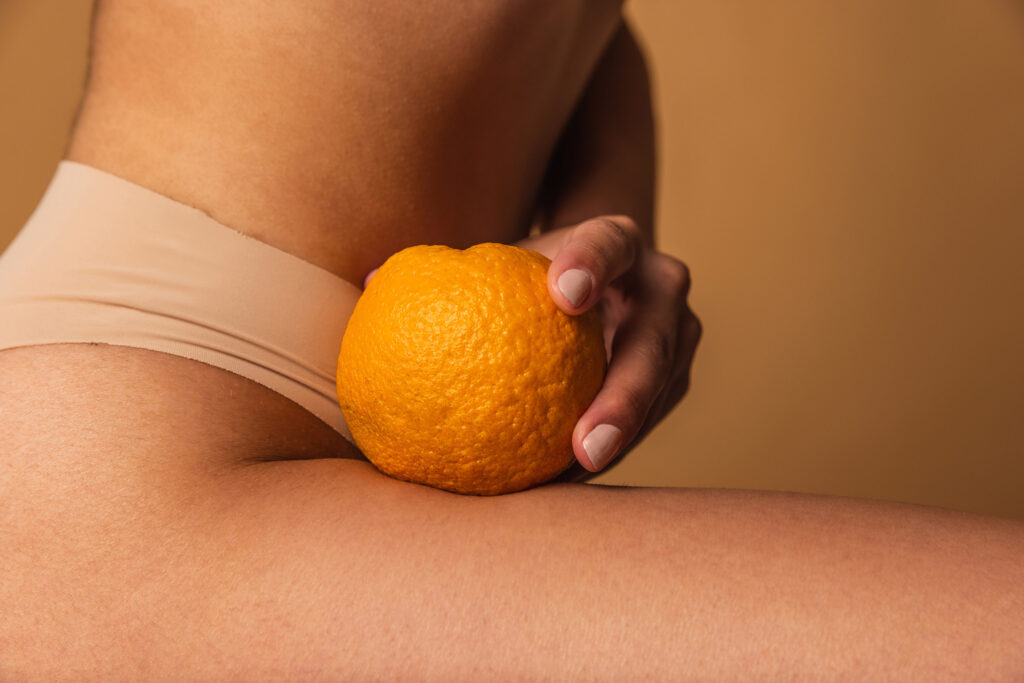 Cropped image of slim young beautiful tanned woman in lingerie posing isolated over brown studio background.