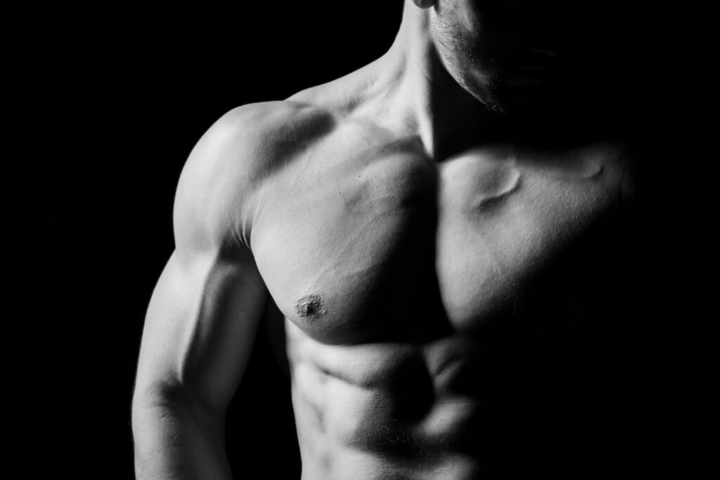 Muscular and sexy torso of young man having perfect abs, bicep and chest. Male hunk with athletic body. Fitness concept. Black and white image