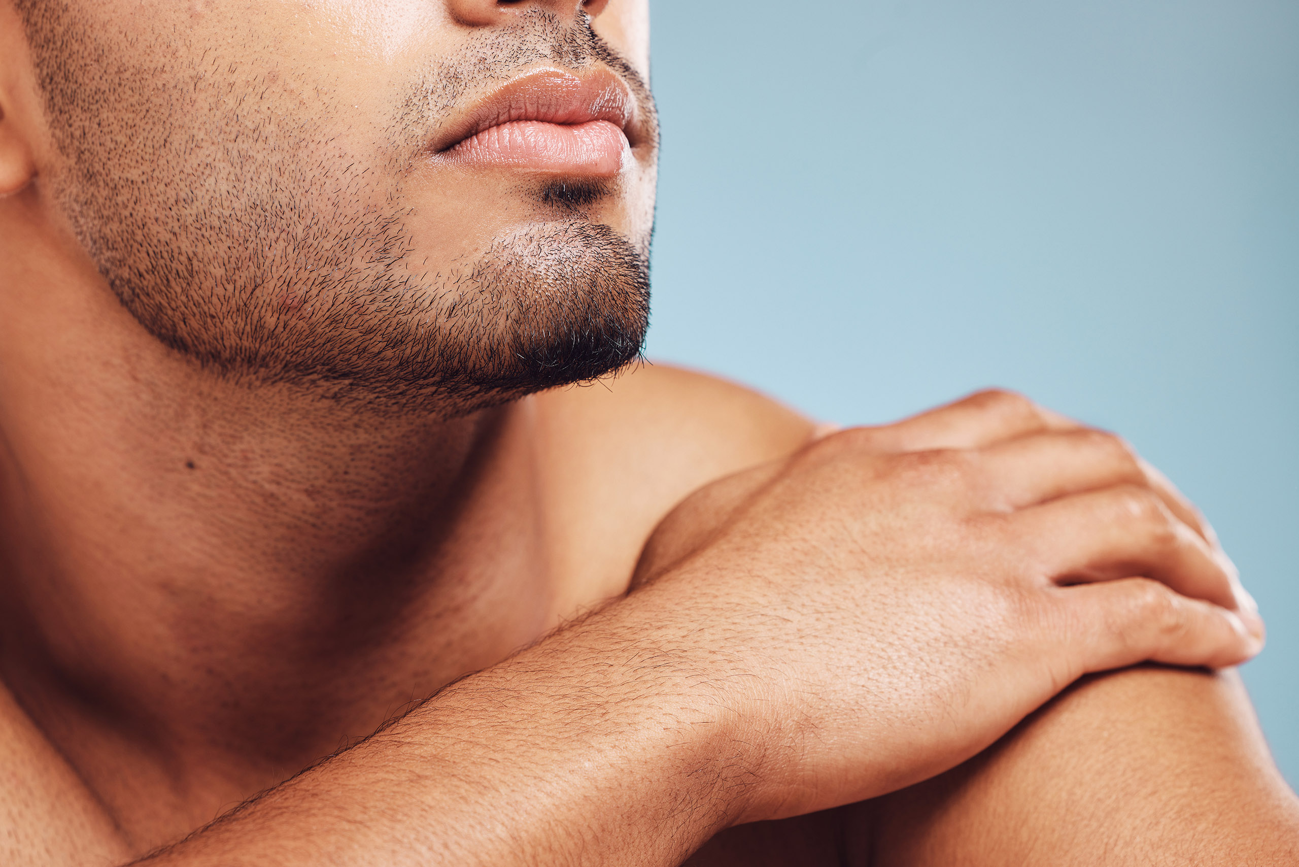 Man, jaw and skincare, face grooming and beard for beauty, aesthetic wellness and healthy skin on studio blue background.