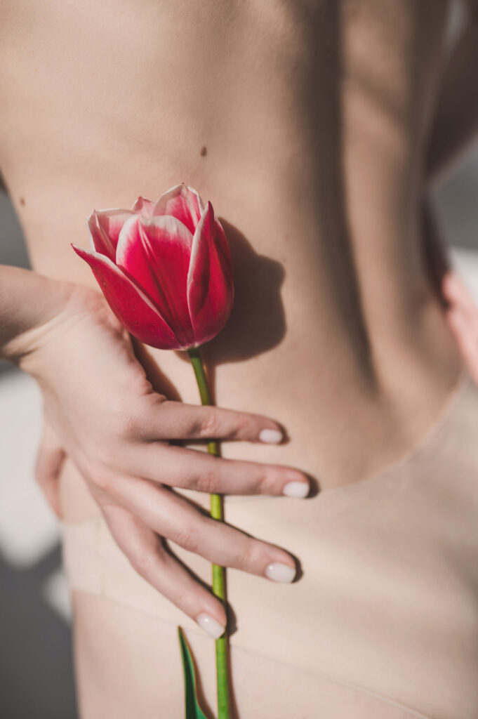 Beautiful woman naked body with flower on her side demonstrating intimate health