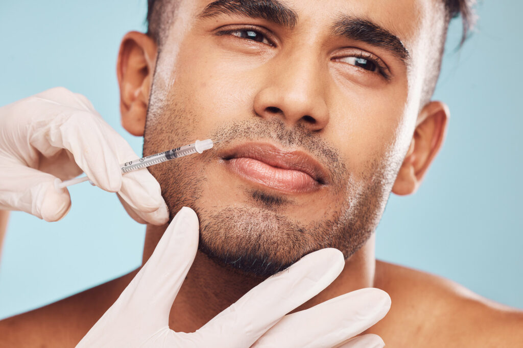 Beauty, botox and mouth with a man in studio on a gray background for a plastic surgery injection. Hands, skincare and syringe with a young male patient indoor for an antiaging facial filler closeup.