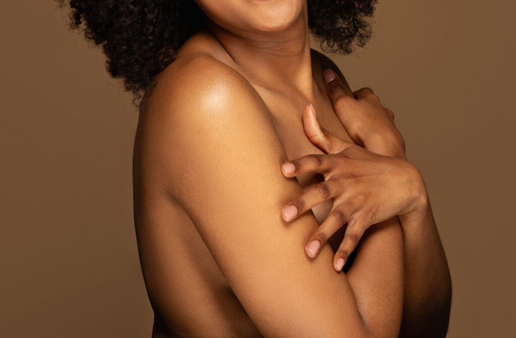 photo shoot of a nude woman with her arms across her chest looking to her left and posed